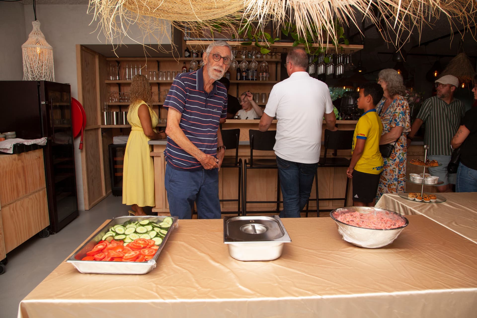 Gasten bij de bar tijdens de opening met buffet op de voorgrond