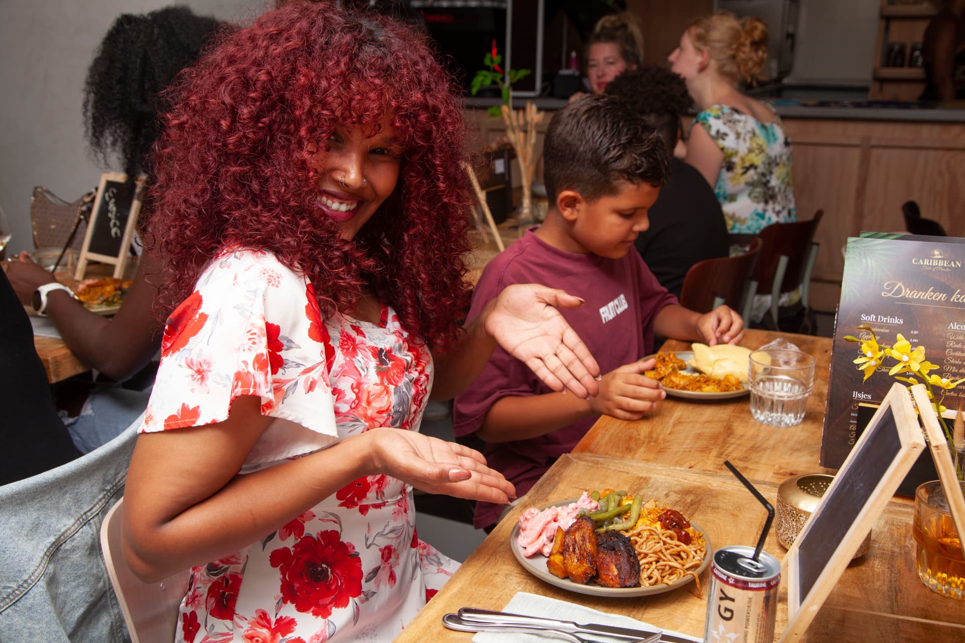 Lachende gast met haar zoon aan tafel met bakbanaan en bami